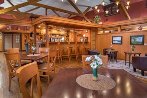 A wooden interior with a bar area, wooden chairs, and a dining table. - Highland Lake Inn & Resort (Flat Rock)