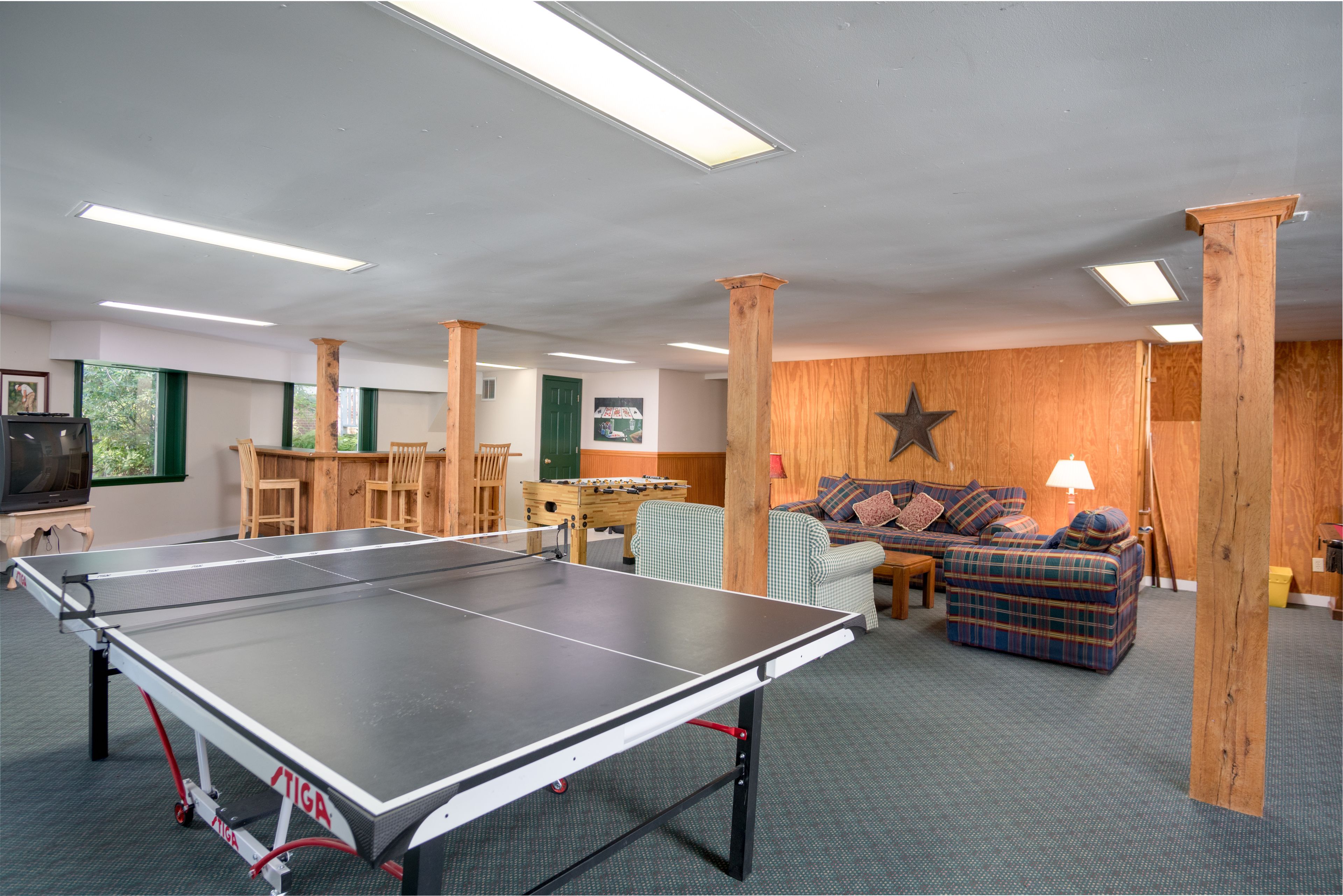 Una stanza con tavolo da ping pong, divano, parete in legno e decorazione a stella.