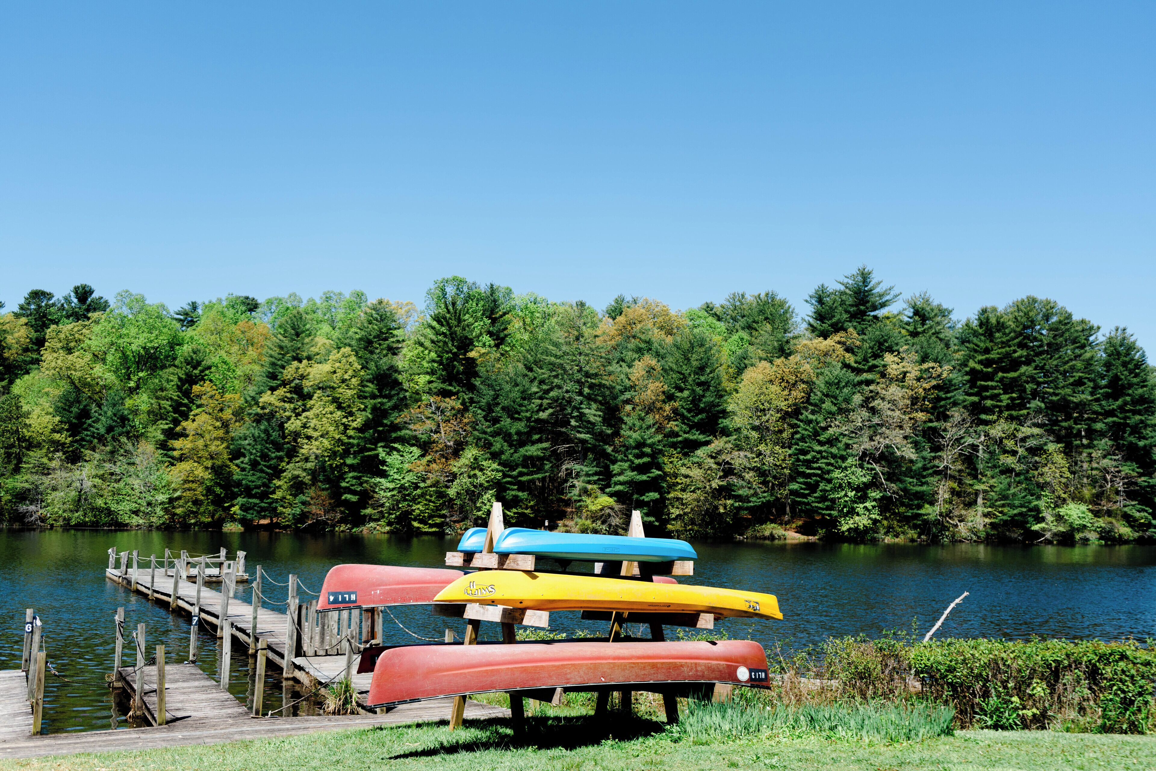 A dock with canoes and a forested lake.