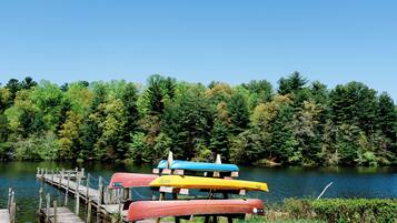 A dock with canoes and a forested lake.