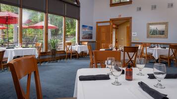 Un restaurante con mesas dispuestas para comer, ventanas amplias y sombrillas exteriores.