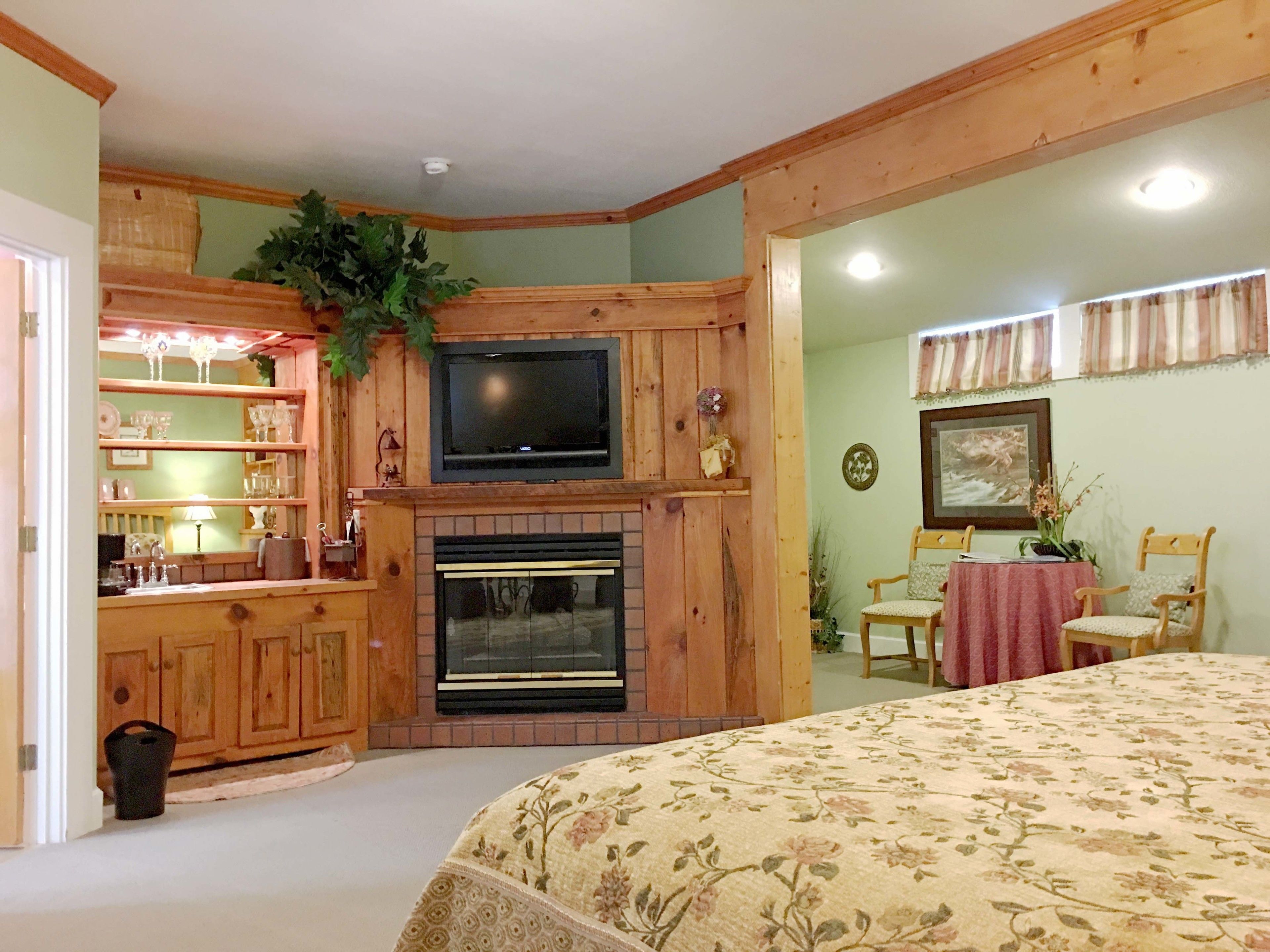 A cozy room with a fireplace, wooden cabinets, a television, and a dining area with a table and chairs.