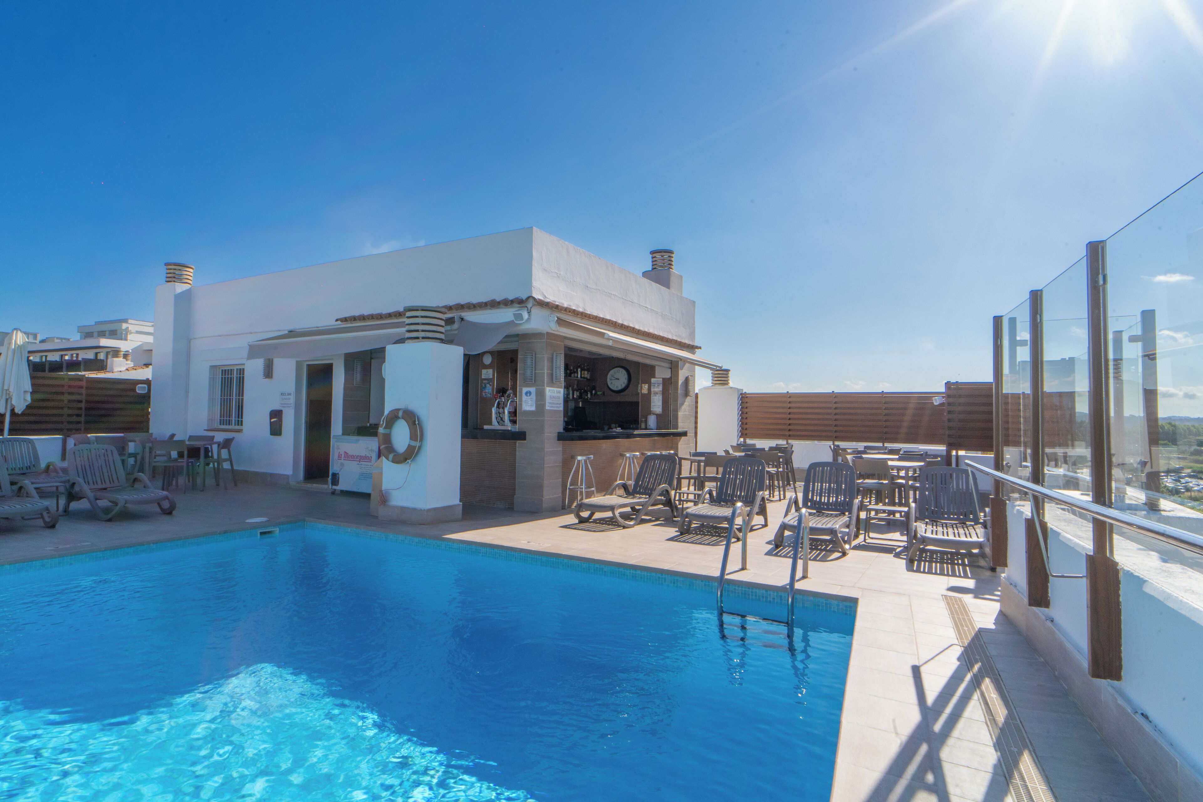 A rooftop pool with lounge chairs and a bar area.