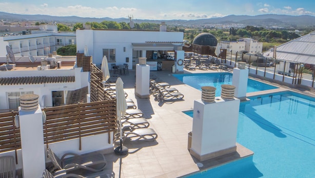 A rooftop pool area with lounge chairs, a bar, and a view of the surrounding landscape. - Sunside Ibiza Studios - Adults Only (Sant Antoni de Portmany)