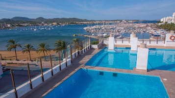 Una piscina al aire libre, sombrillas, sillones reclinables de piscina