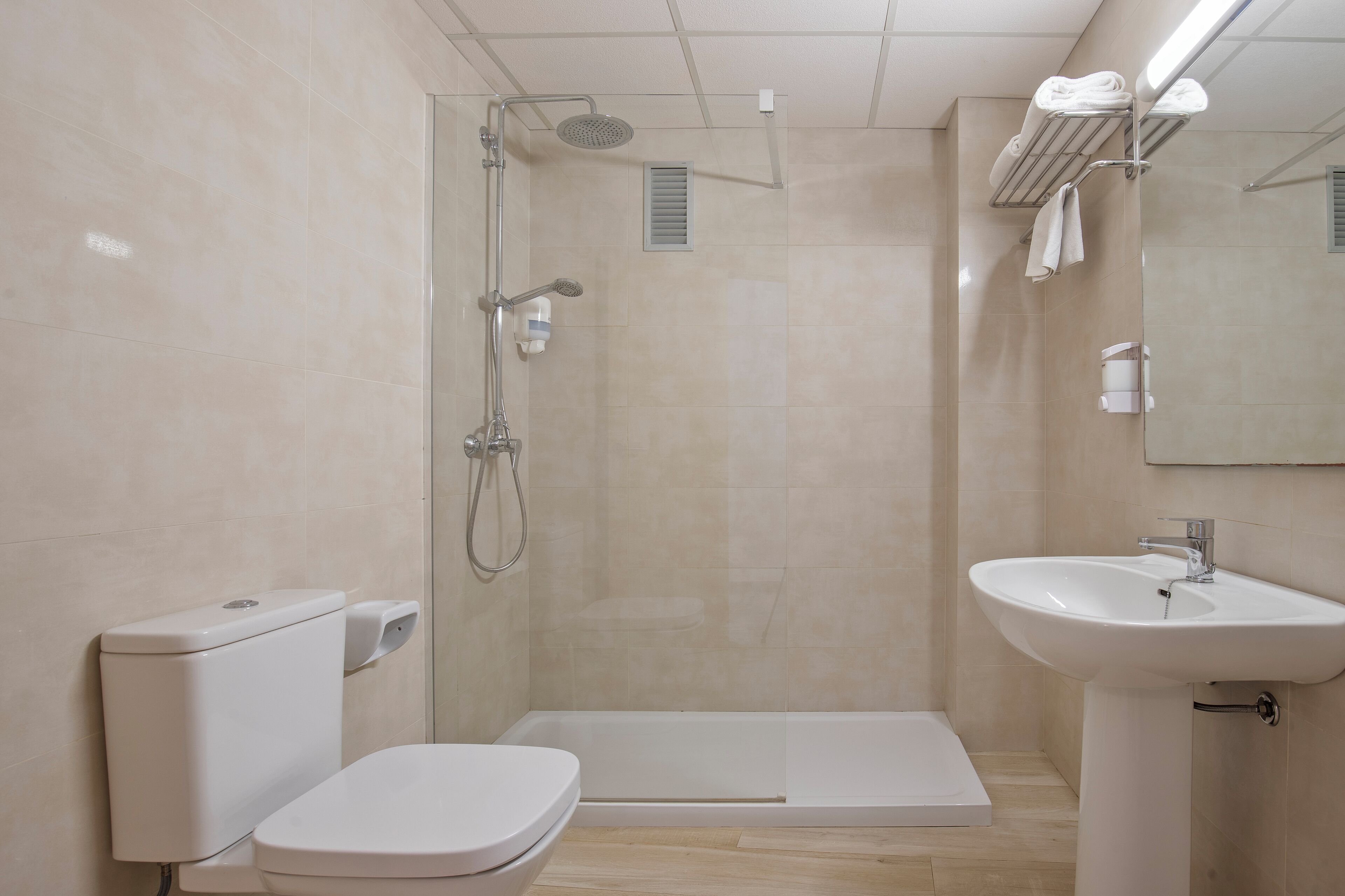 A modern bathroom with a toilet, shower, and sink.
