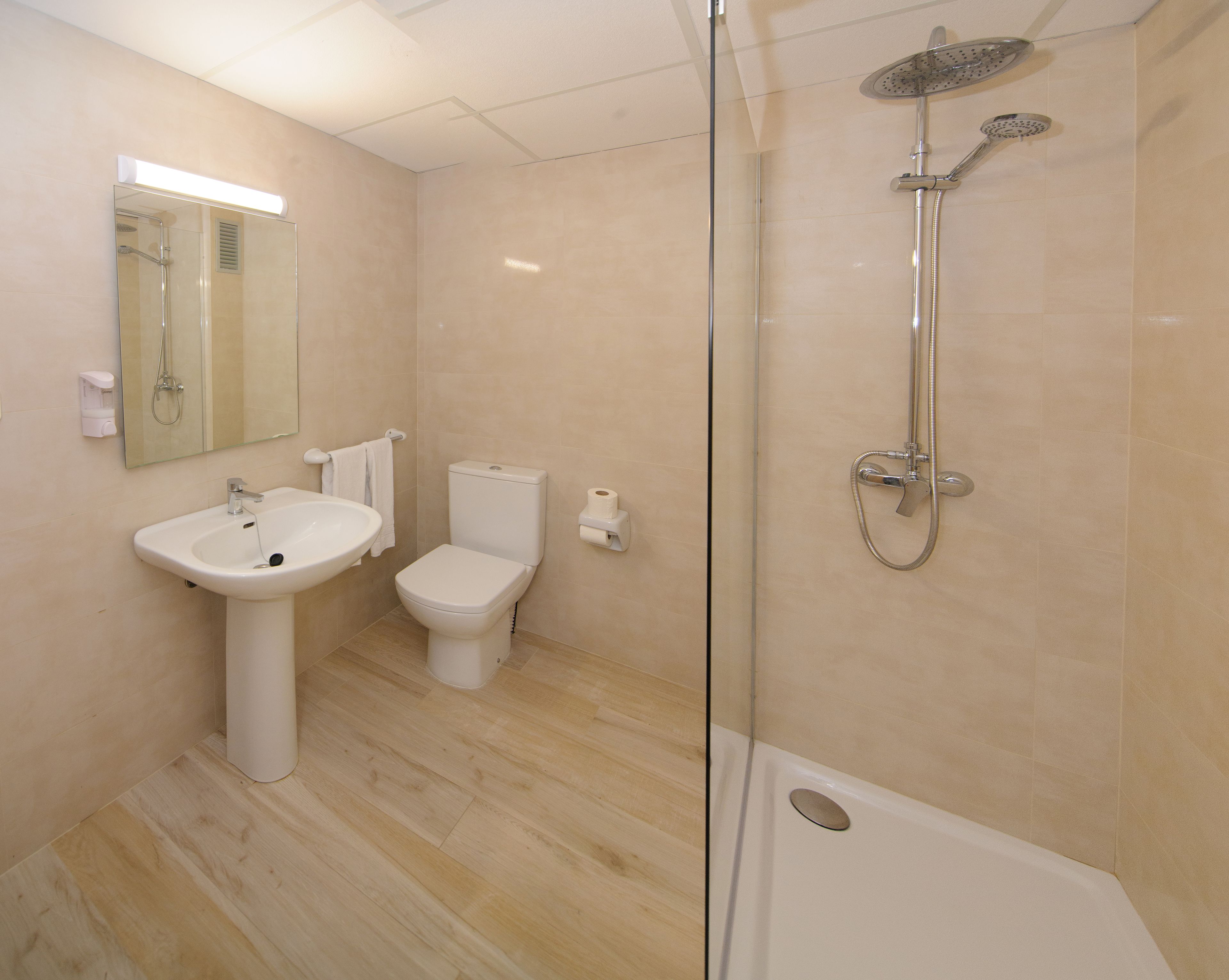 Une salle de bain moderne avec une douche à parois de verre, un lavabo sur colonne et des toilettes.