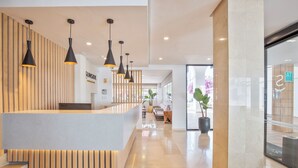 A modern reception area with a wooden reception desk, black pendant lighting, and a potted plant. - Sunside Ibiza Studios - Adults Only (Sant Antoni de Portmany)