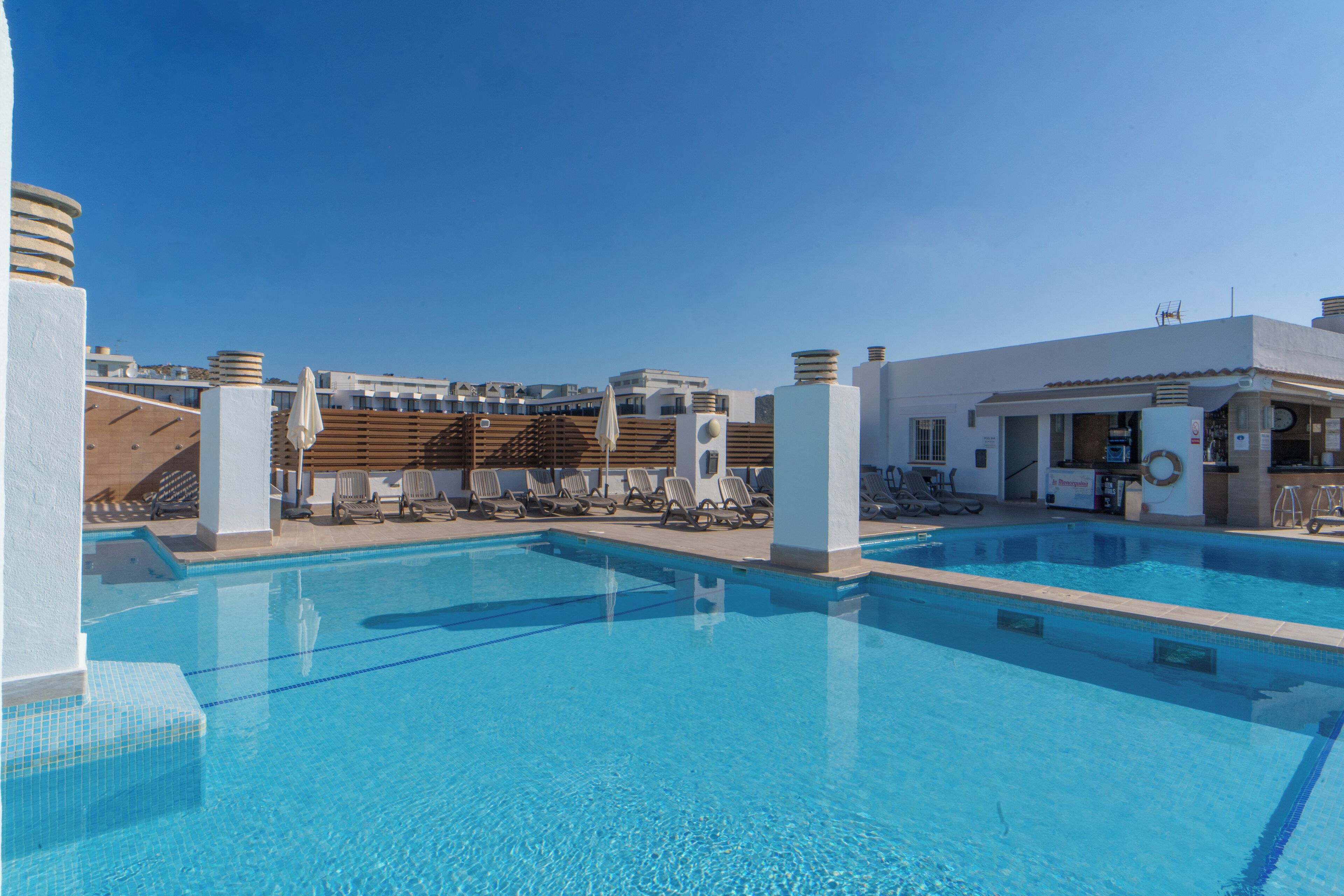 A swimming pool with lounge chairs and a bar area.