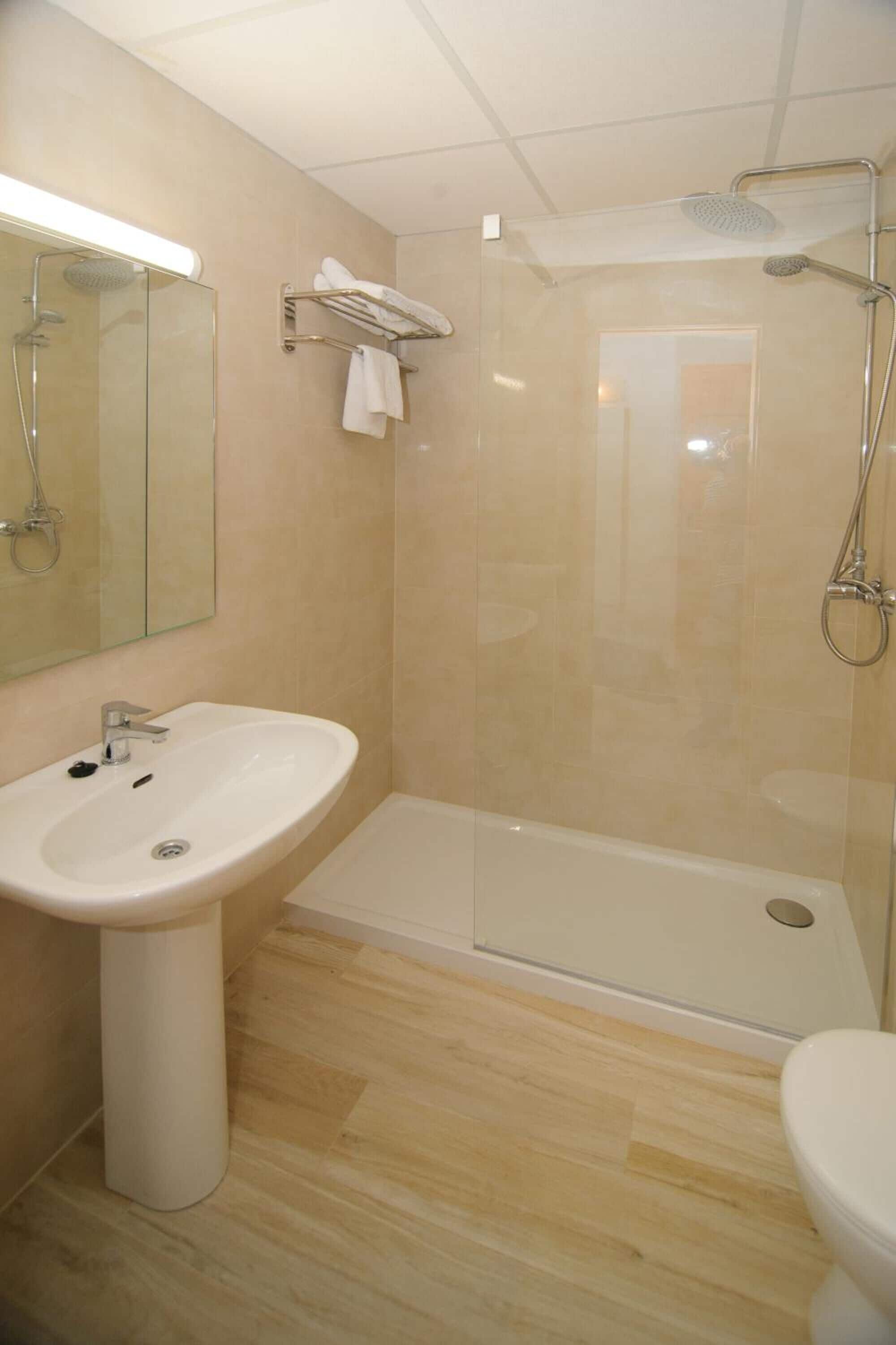 Une salle de bain moderne avec une douche à parois de verre, un lavabo sur colonne et des toilettes.