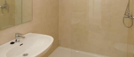 A modern bathroom with a glass-enclosed shower, a pedestal sink, and a toilet.