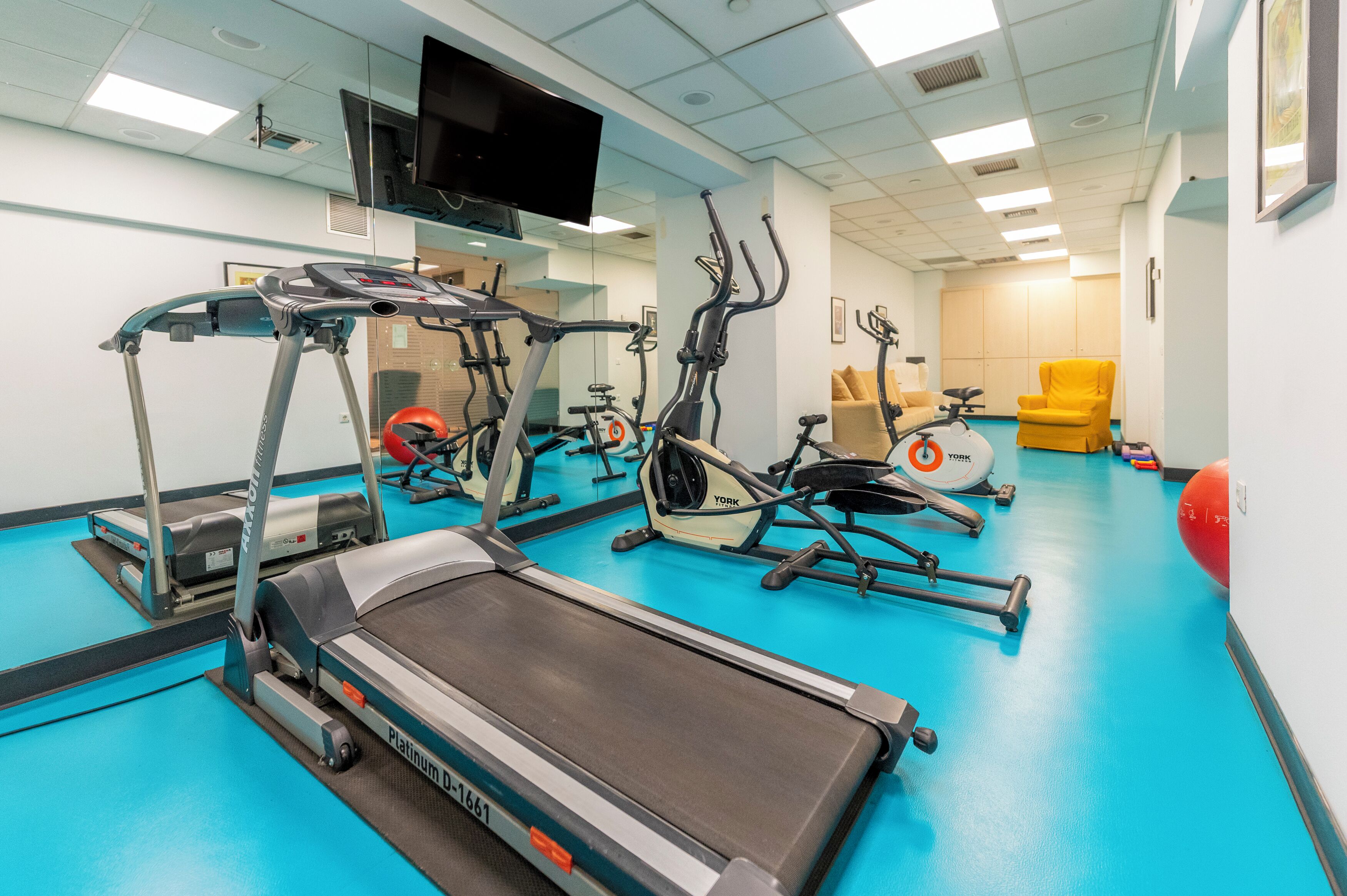 A gym with treadmills, stationary bikes, and exercise balls.