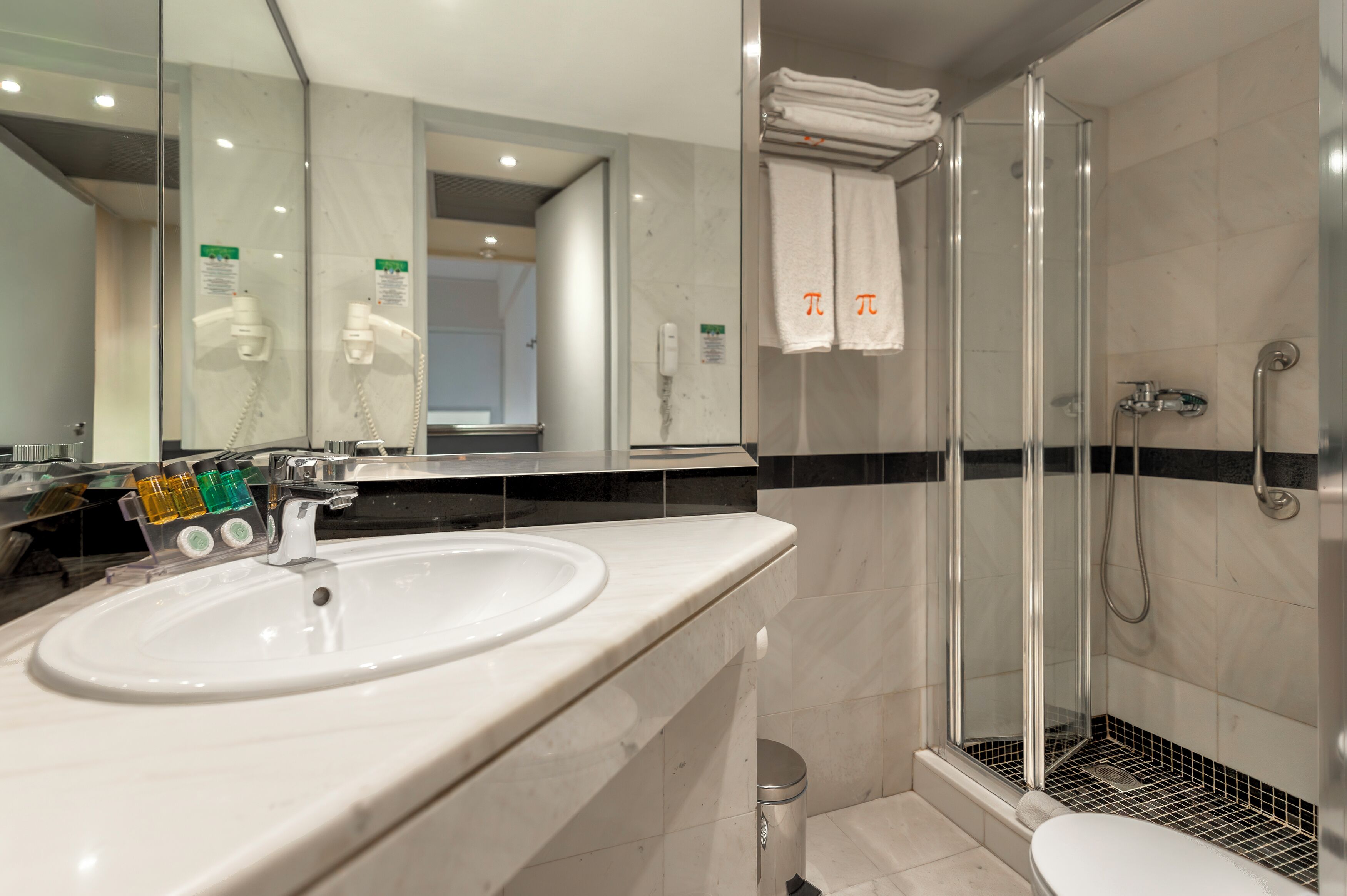 A bathroom with a sink, mirror, shower, and toilet.