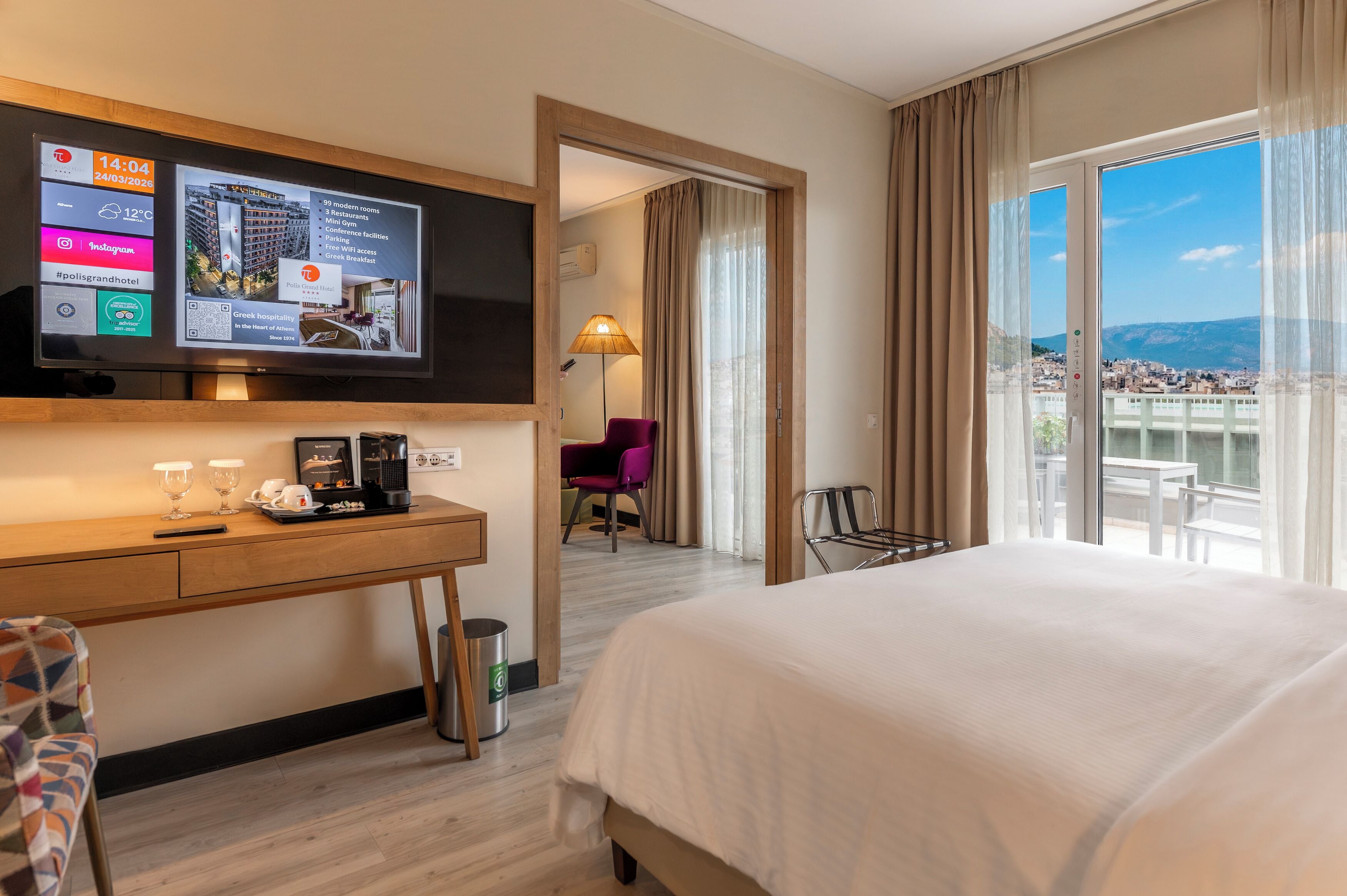 A hotel room with a bed, desk, TV, and a balcony with a view.