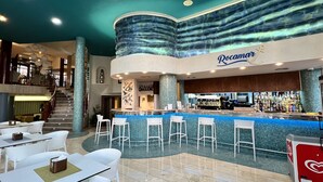 Un espace bar agrémenté d’une enseigne « Rocamar », une piscine aux carreaux bleus et un escalier menant à un niveau supérieur.