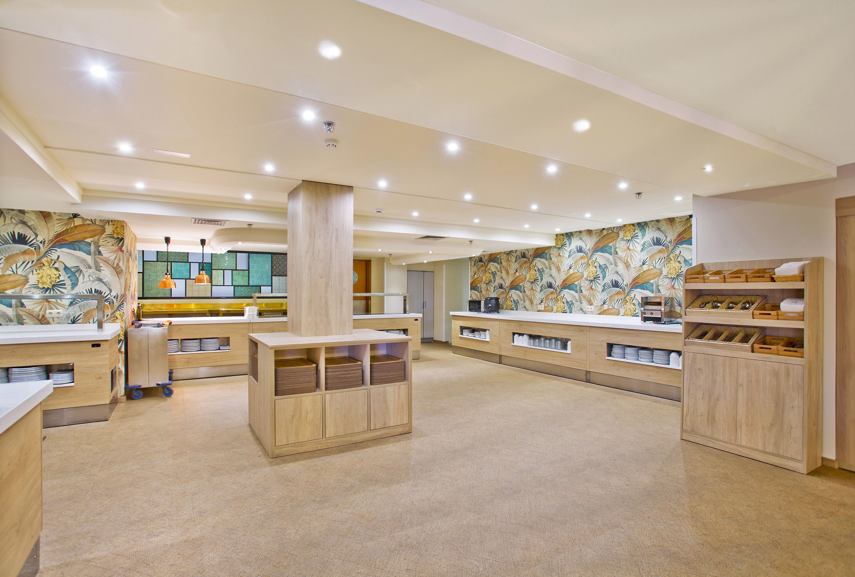 A spacious, well-lit room with wooden cabinets and countertops, featuring a tropical mural on the wall.