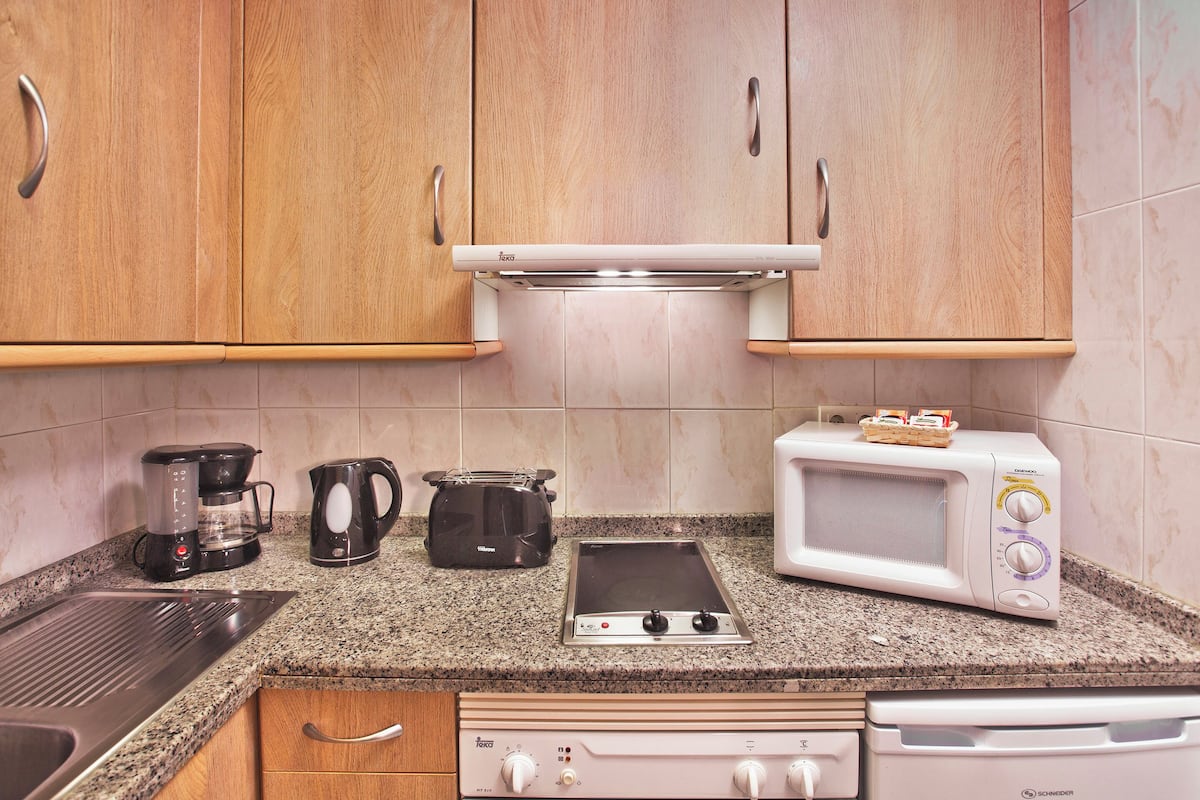 A kitchen with wooden cabinets, a coffee maker, a toaster, a microwave, and a stove.