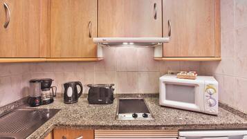 Cozinha com armários de madeira, cafeteira, torradeira, micro-ondas e fogão.