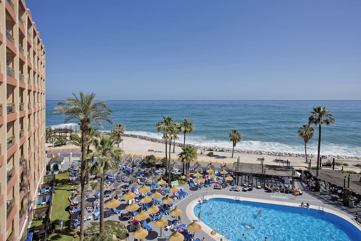 A hotel with a pool, beach, and ocean view.