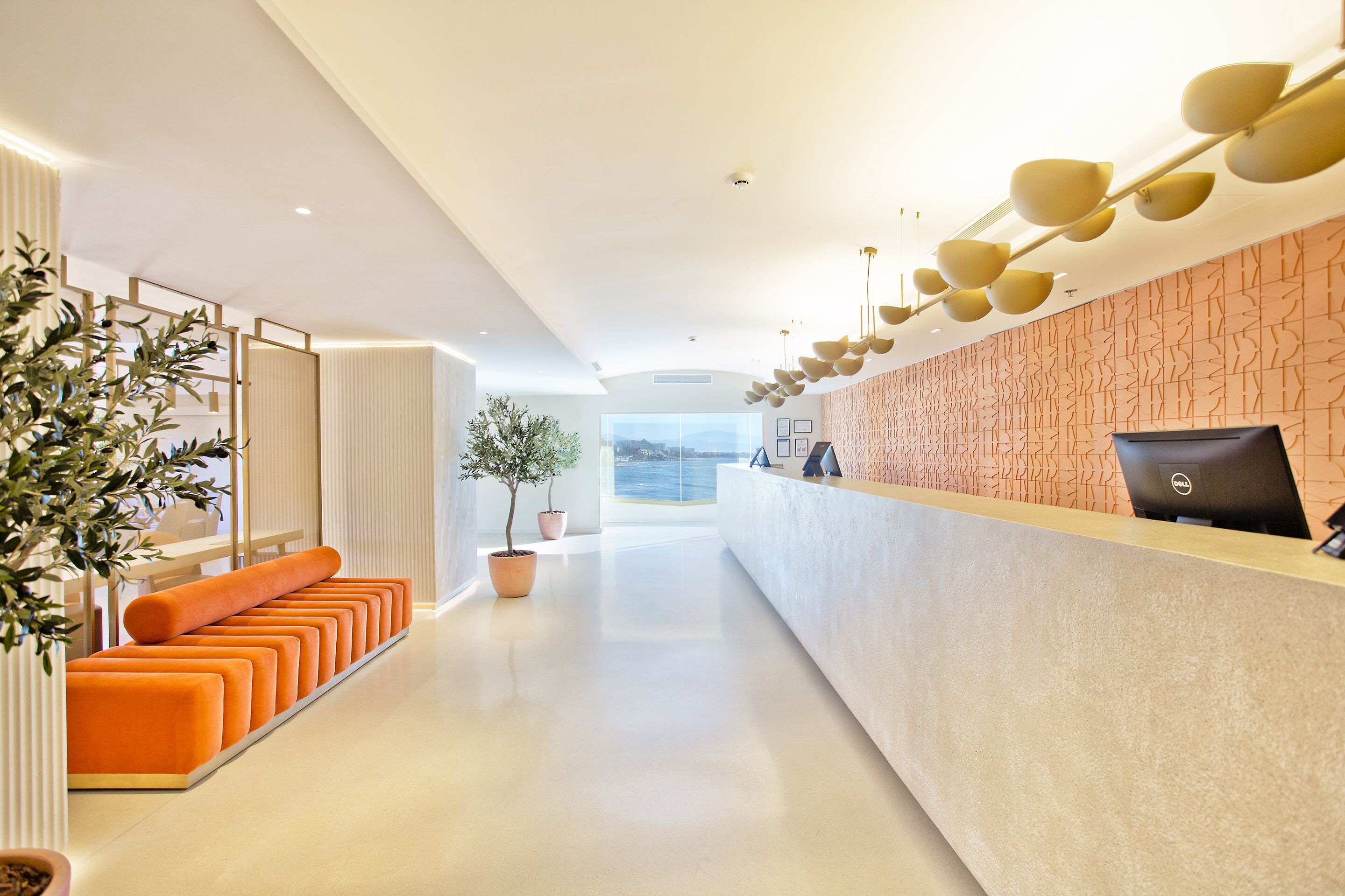 Ett modernt receptionsområde med en lång receptionsdisk, orange sittmöbler och utsikt över omgivningen.