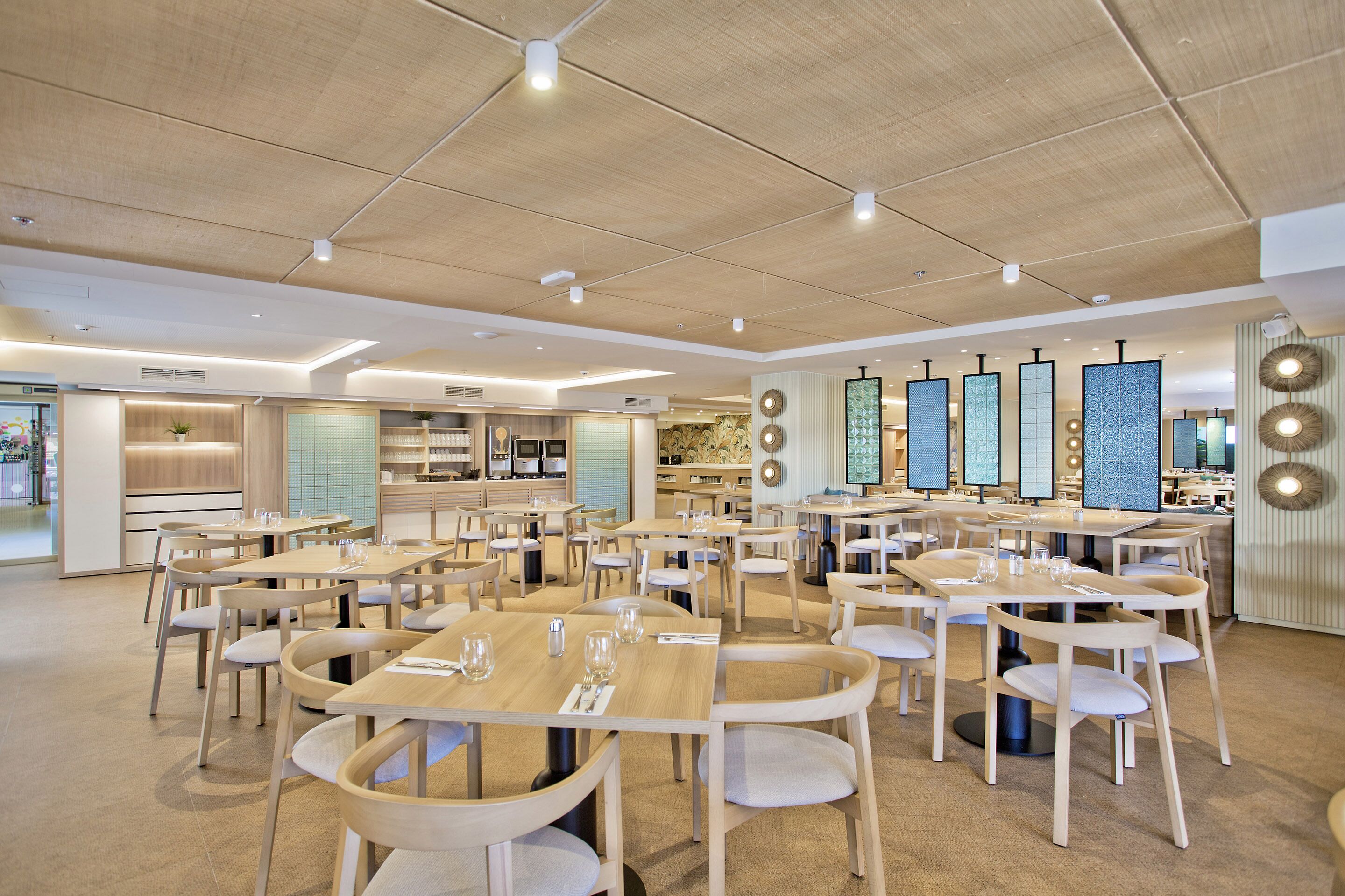 Ein geräumiges Restaurant mit mehreren Tischen und Stühlen, einer Holzbalkendecke und dekorativen Wandverkleidungen.