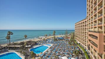 En resort med flere swimmingpools, lounges ved stranden og en stor bygning med altaner.