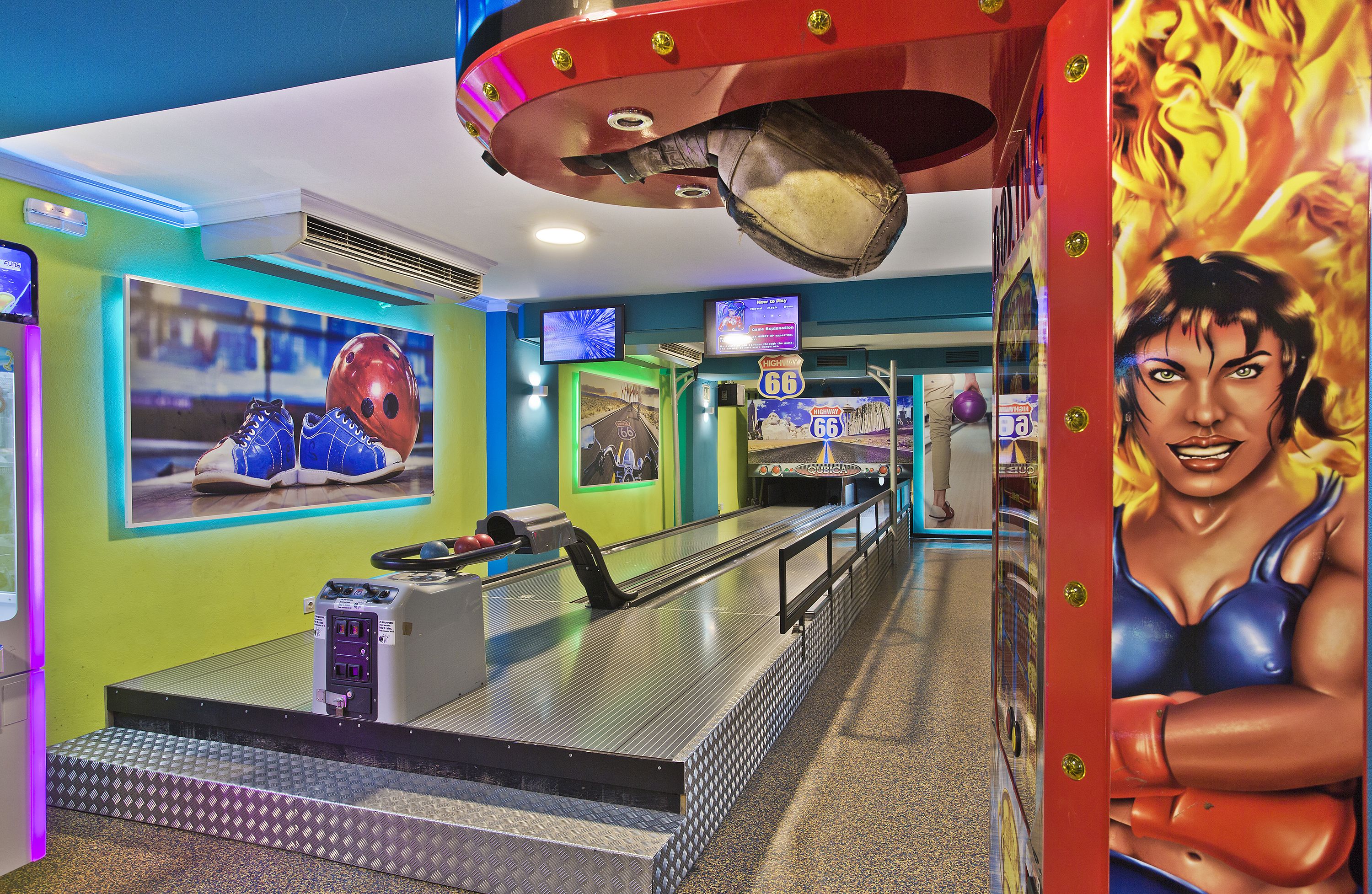 A bowling alley with a bowling lane, pinsetter, and a large mural of a woman.