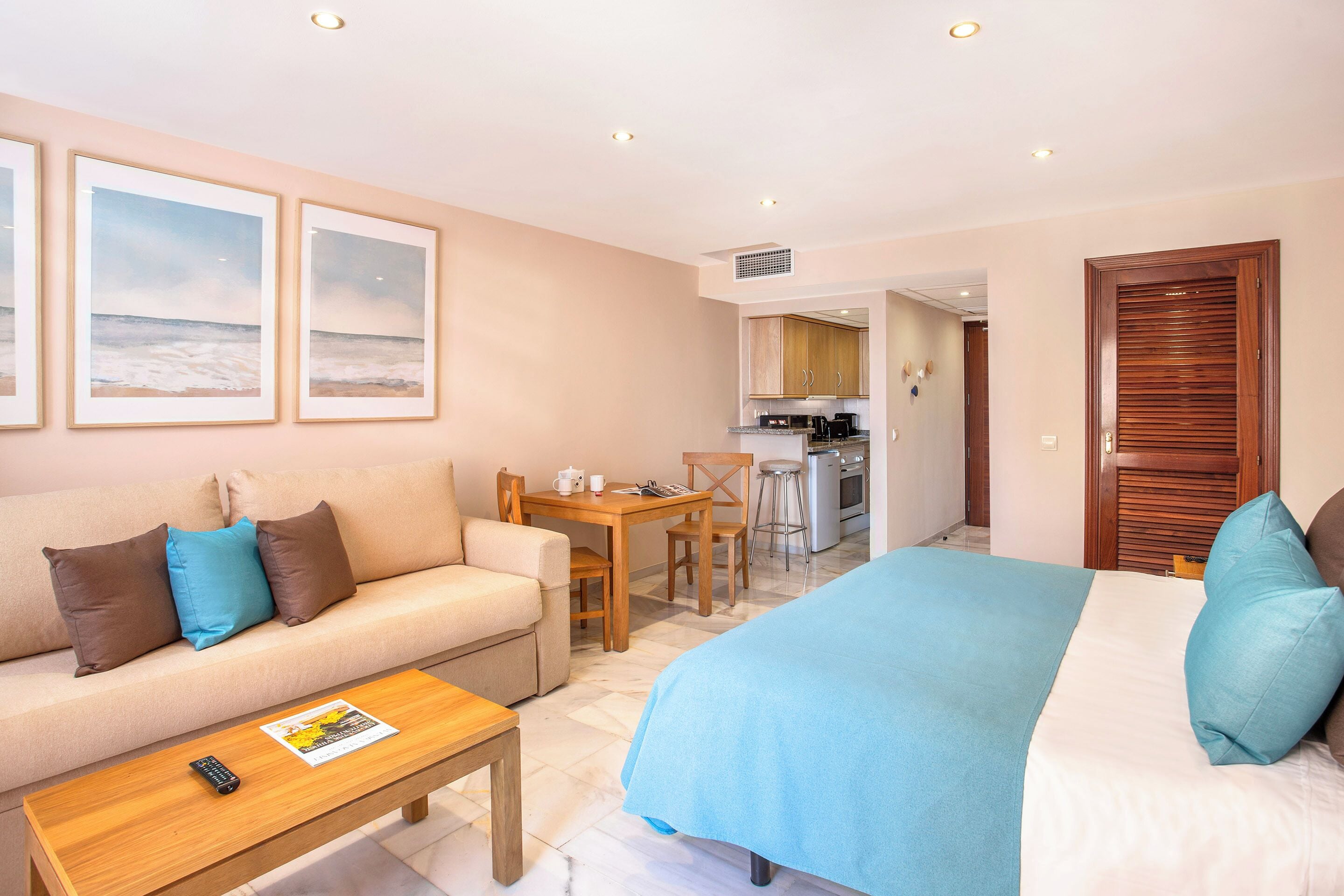 Une chambre d’hôtel comprenant un lit, un canapé, une table à manger et un coin cuisine.