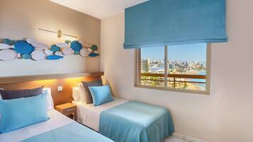 A hotel room with two beds, a city view, a wall decoration, and a window with a view.