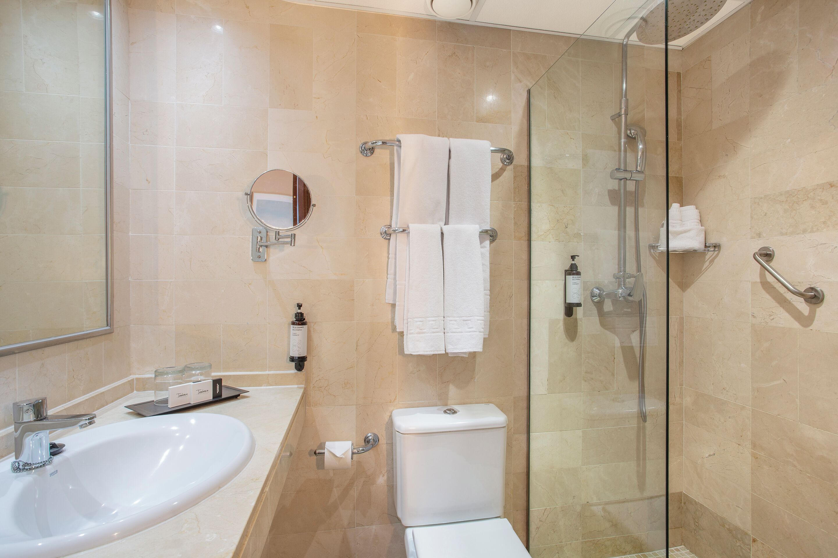 Bany amb dutxa tancada per vidre, un lavabo, un vàter i un mirall.
