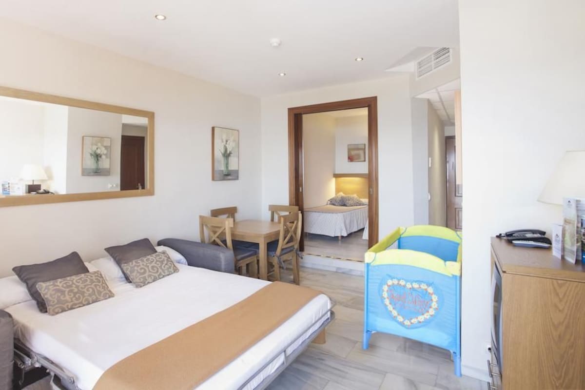 Una habitación de hotel con cama, escritorio, silla y espejo.