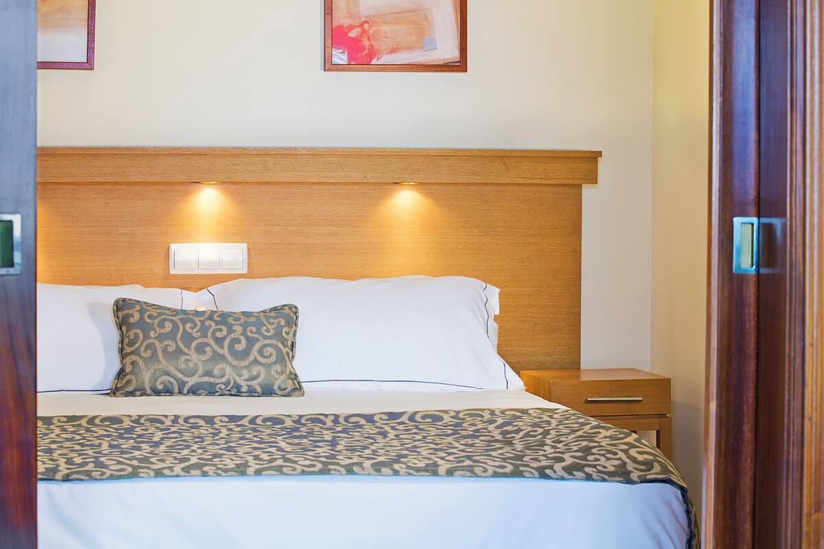 A neatly made bed with a patterned bedspread, a wooden headboard, and bedside lamps.