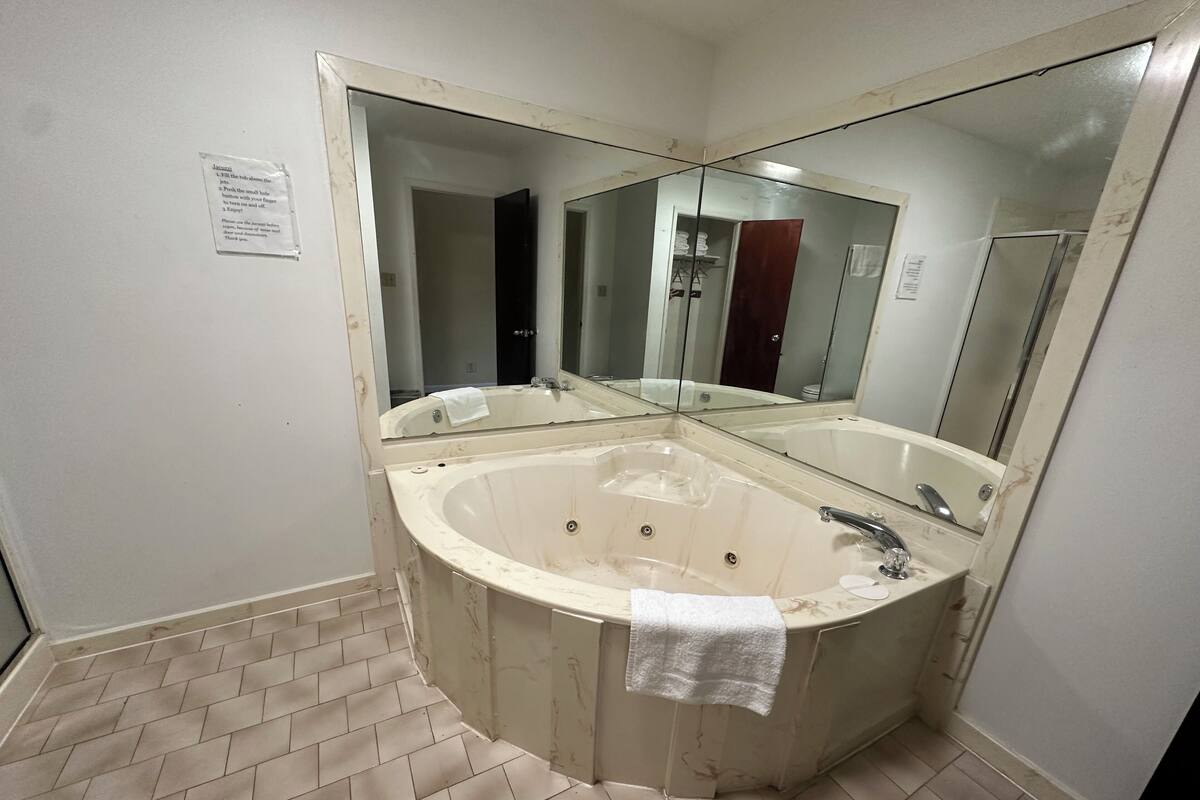 Un baño con una bañera grande, un lavabo y un espejo.