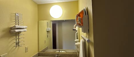 A bathroom with a sink, mirror, towel rack, and a round light fixture.