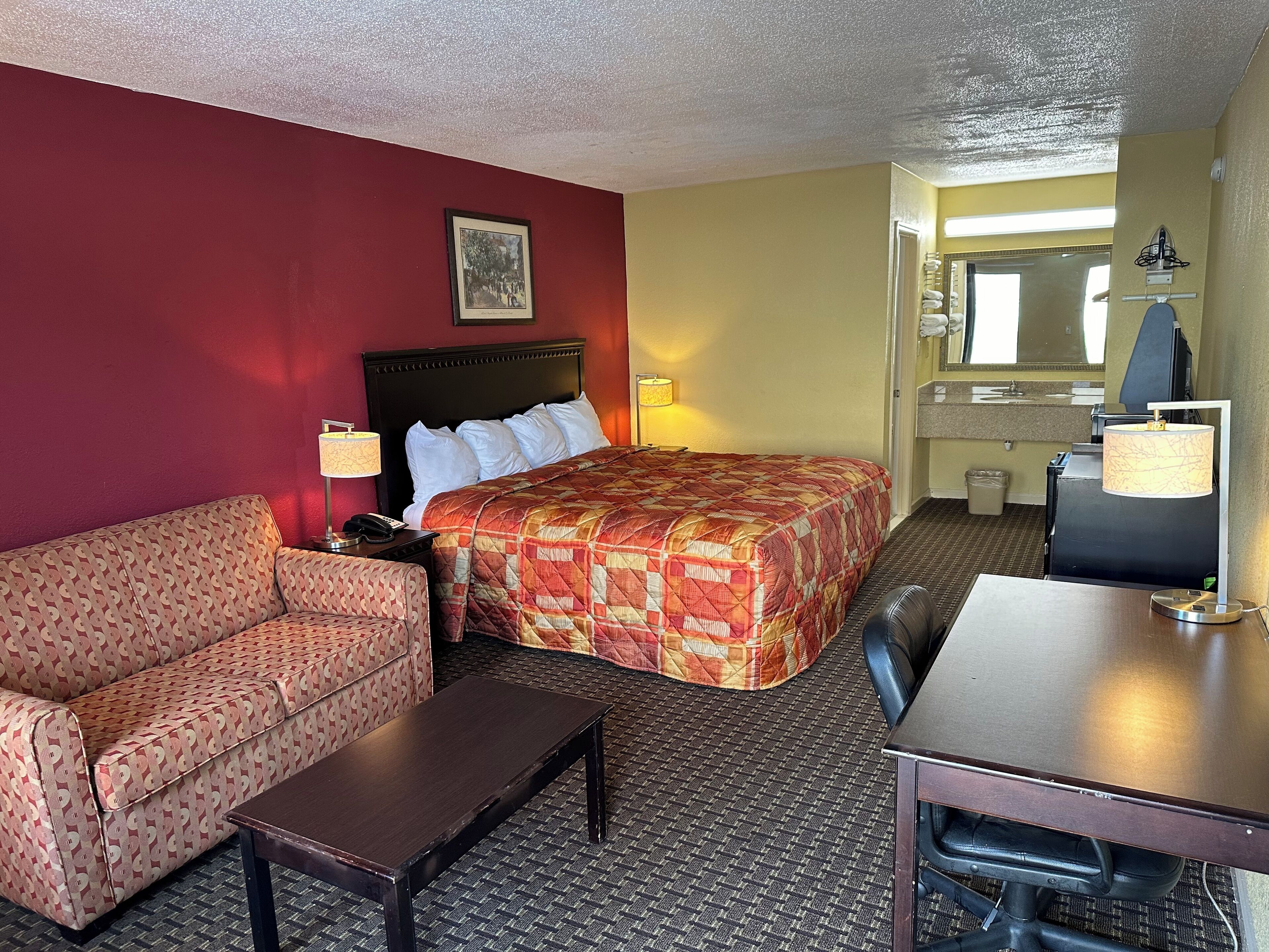 Quarto de hotel com cama, sofá, escrivaninha e cadeira.