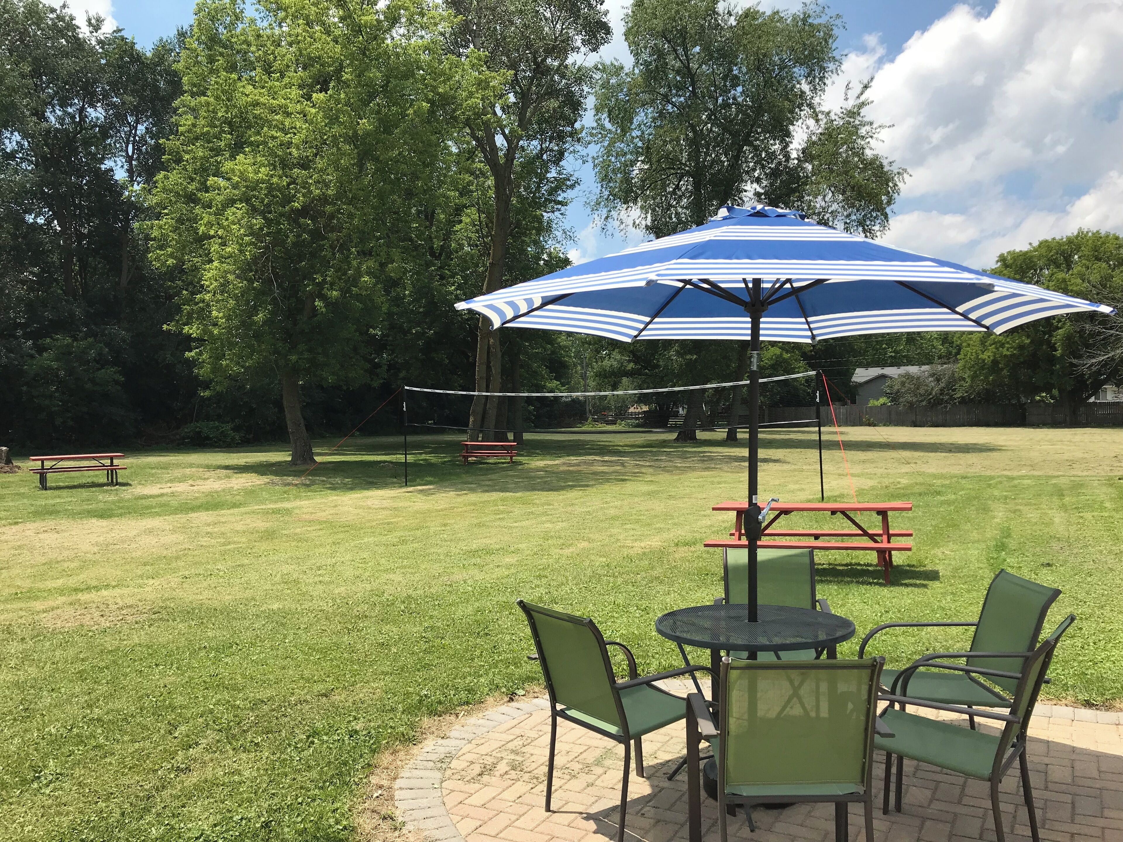 A patio area with a table and chairs, a picnic table, and a volleyball net.