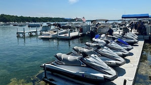 Un port de plaisance où sont amarrés différents types de bateaux, notamment des jet-skis et un bateau à moteur.