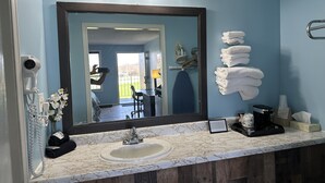 Une salle de bain avec un lavabo en marbre, un grand miroir et un porte-serviettes avec des serviettes pliées.