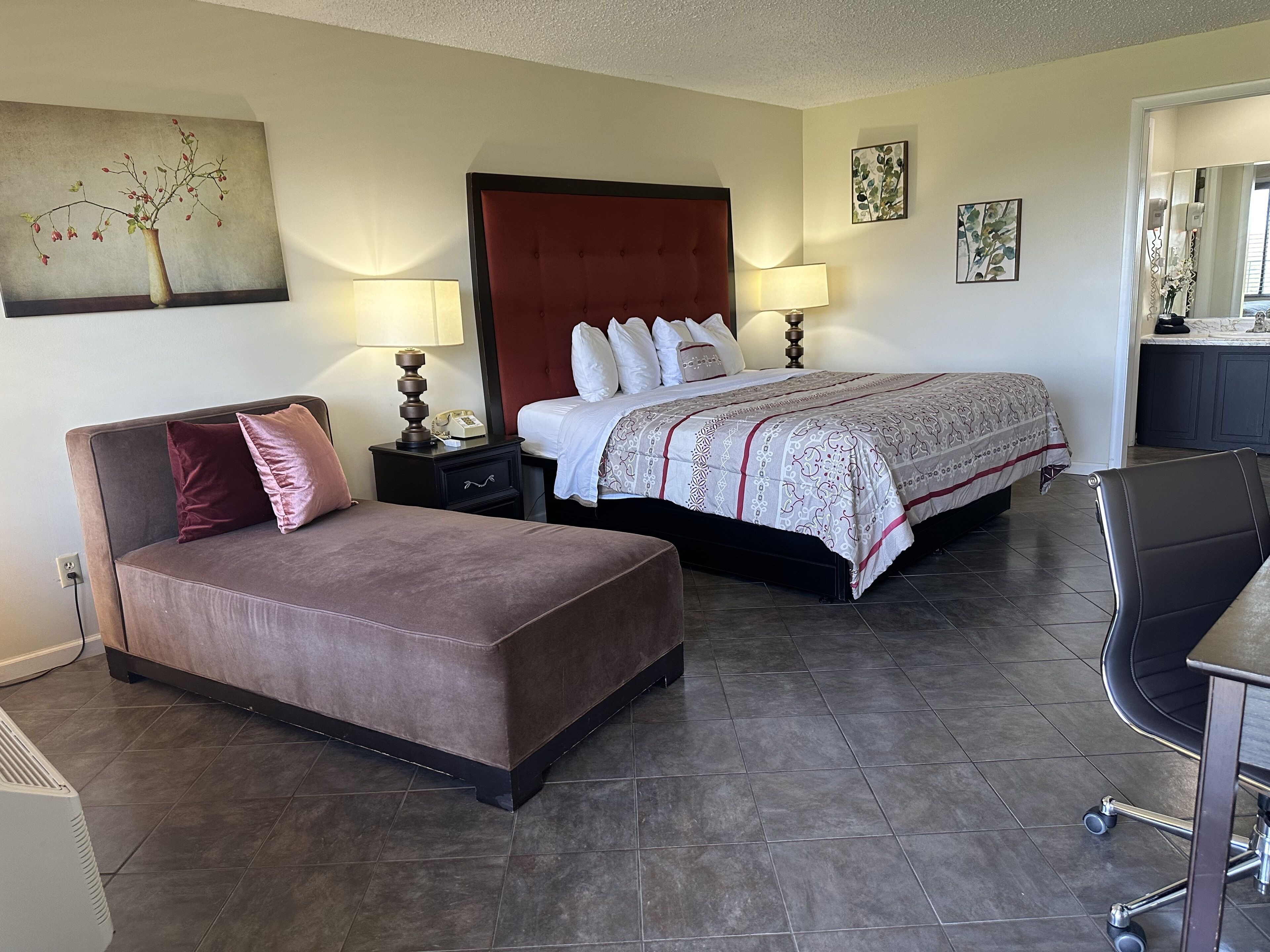 A hotel room with a bed, a sofa, a desk, and a chair.