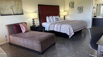 A hotel room with a bed, a sofa, a desk, and a chair.