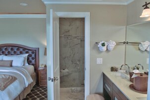 A hotel room with a bed, a bathroom with a shower, and a sink with towels.