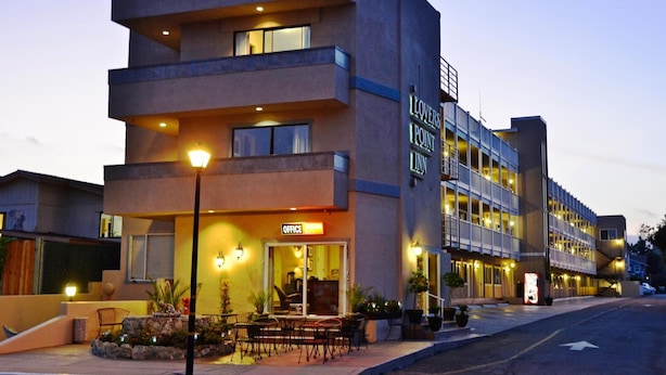 Un hotel de diversos pisos amb un disseny modern, amb un cartell ben visible de 'Lovers Point Inn', zona d'seients a l'aire lliure i un cartell d' 'Office' que indica un espai de treball.