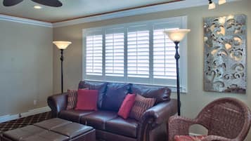A living room with a leather sofa, a wicker chair, a floor lamp, and a decorative wall piece.