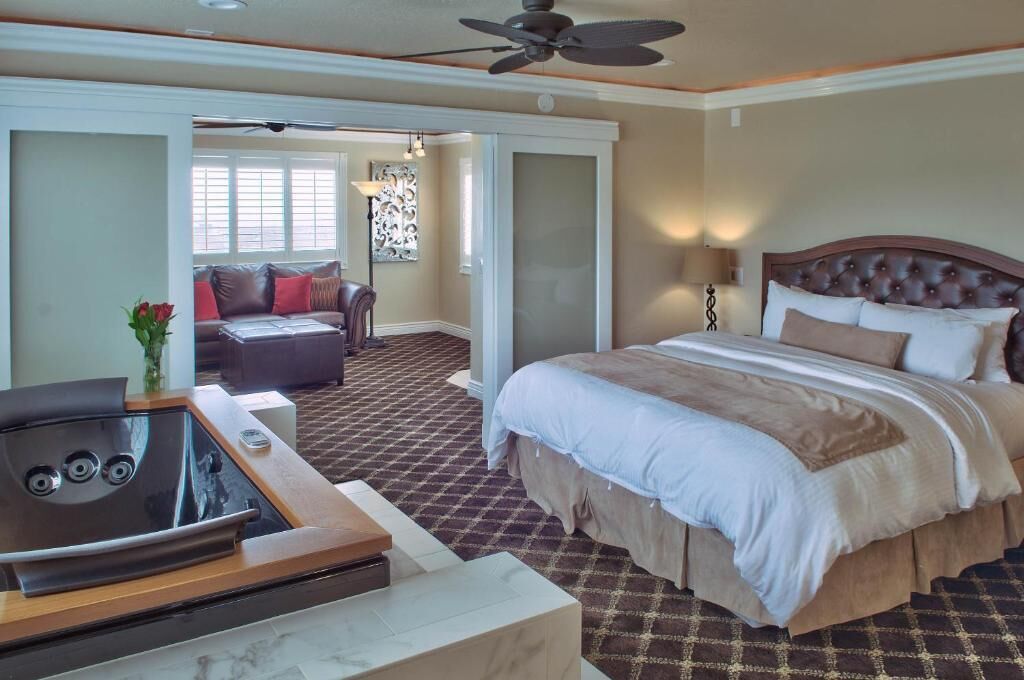 A hotel room with a bed, a seating area with a sofa, a coffee table, and a ceiling fan.