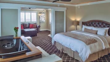 A hotel room with a bed, a seating area with a sofa, a coffee table, and a ceiling fan.