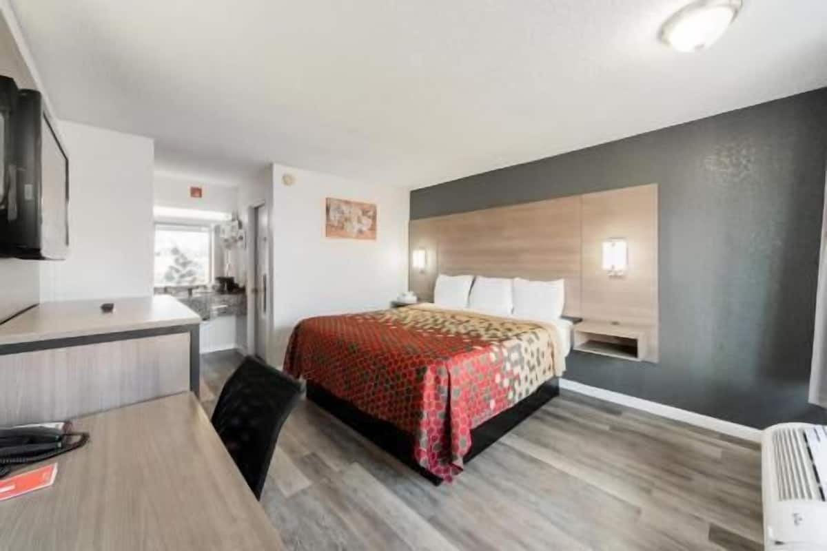 Una habitación de hotel con cama, escritorio y kitchenette.