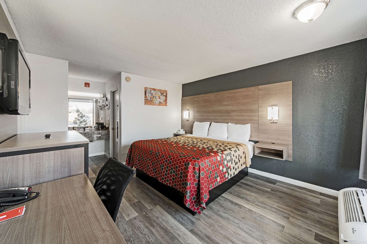 Una habitación de hotel moderna con una cama, un escritorio y una kitchenette.