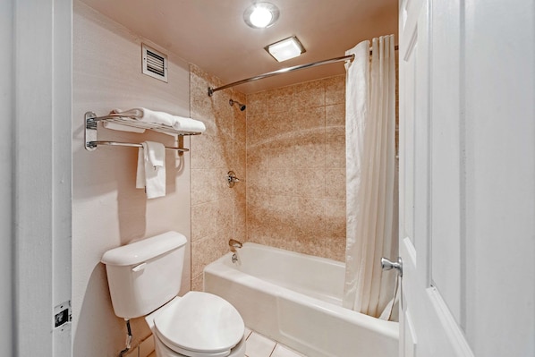 Un baño con inodoro, bañera y cortina de ducha.