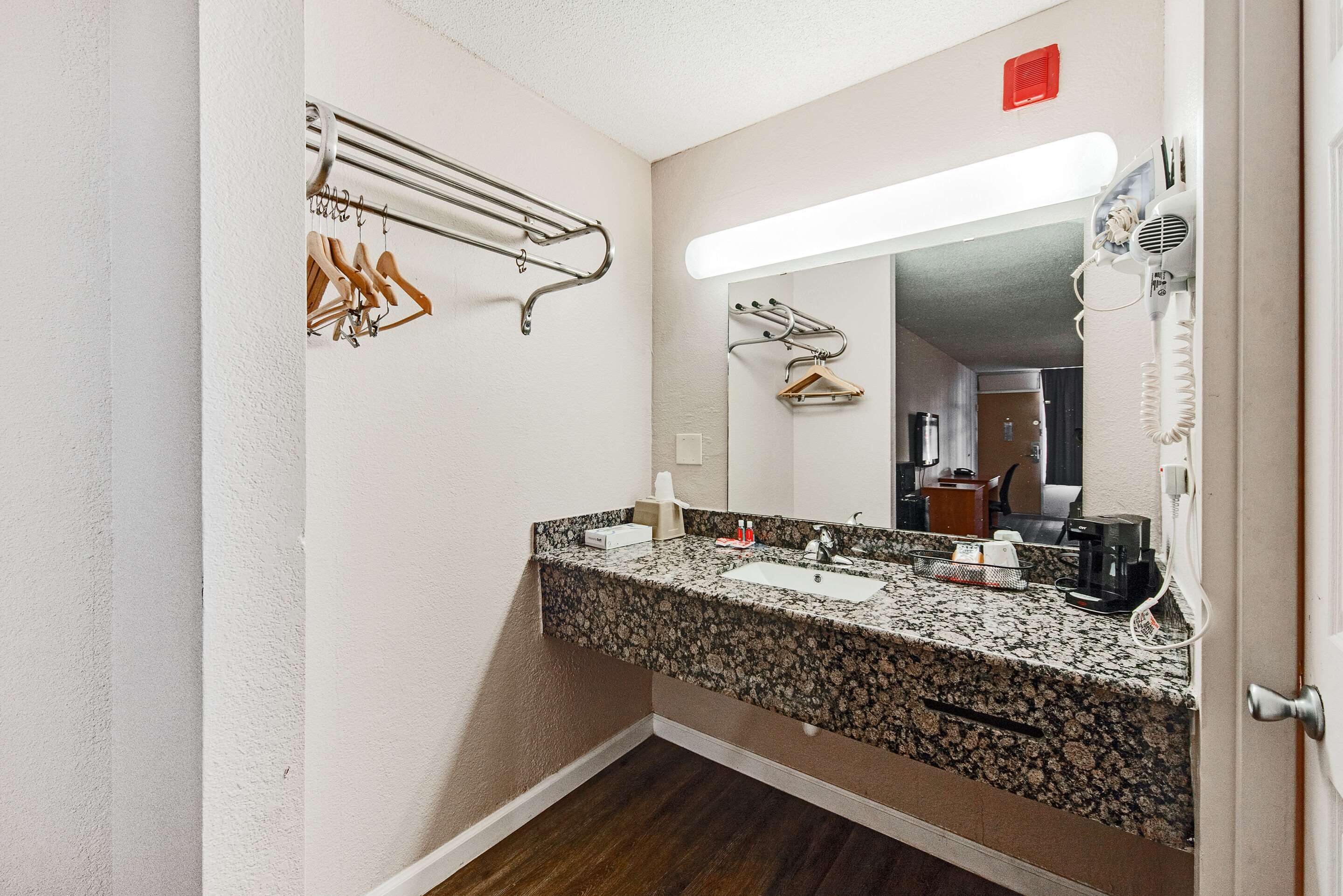 Une salle de bain avec un lavabo doté d’un plan de travail en granit, un miroir, un porte-serviettes et un sèche-cheveux.