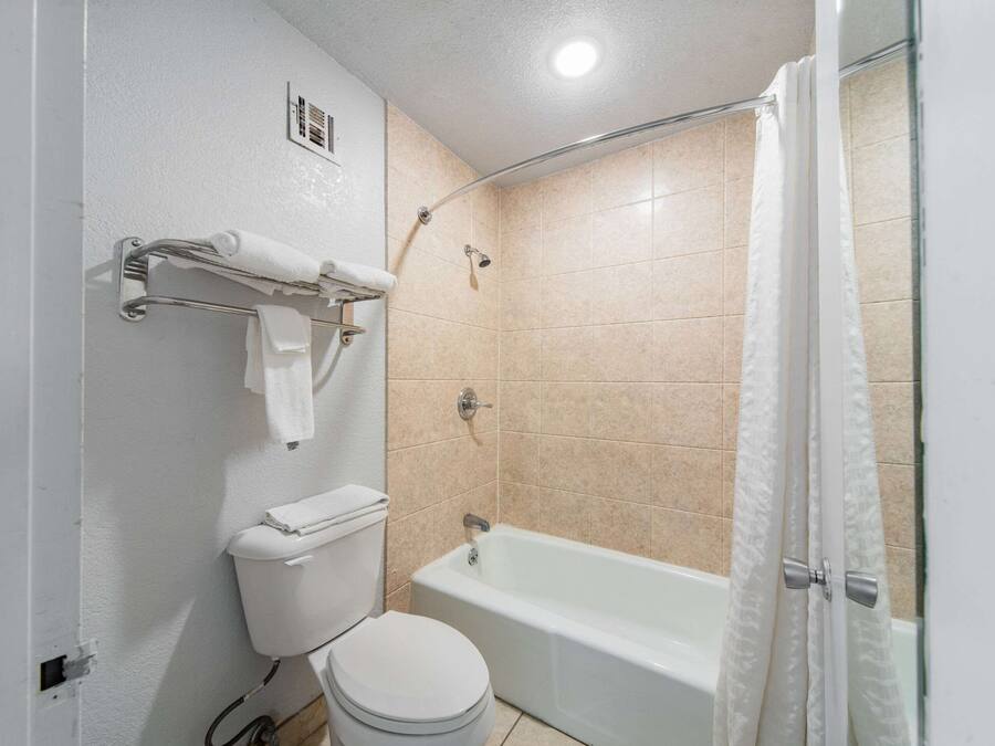 Une salle de bain équipée de toilettes, d’une baignoire et d’un rideau de douche.